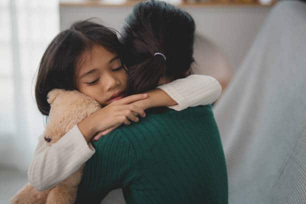 A young girl hugging an adult woman, offering comfort and support during a difficult time.