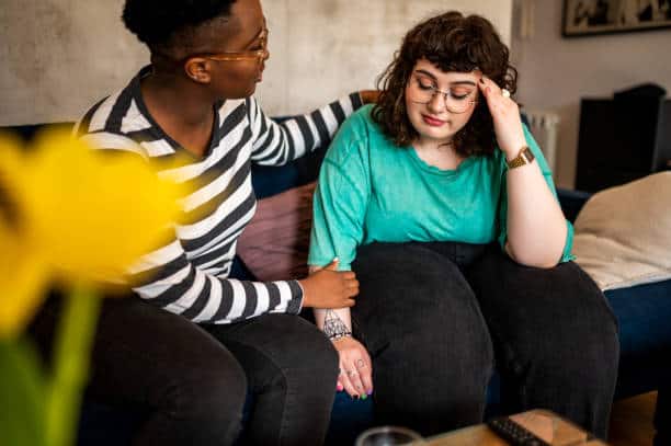 Supportive woman comforting a distressed young woman feeling overwhelmed or upset.
